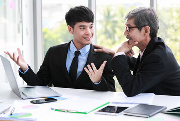 Successful young adult Asian businessman explaining about an idea for solving the problem to professional senior managers with smiling. A man working with a modern digital laptop on the table