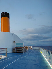 Modern cruiseship or cruise ship liner with yellow funnel at sea during twilight blue hour sunrise...