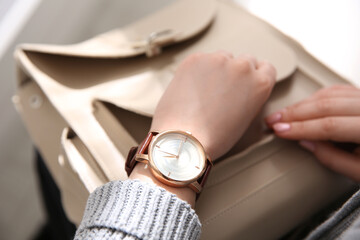 Woman with luxury wristwatch and handbag on blurred background, closeup