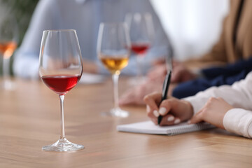 Sommeliers making notes during wine tasting at table indoors, closeup