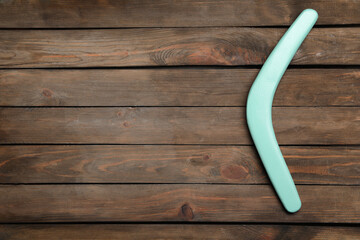 Boomerang on wooden background, top view. Space for text