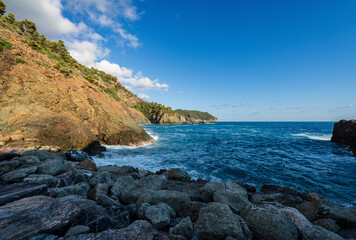 Fototapeta na wymiar Rocky beach and Cliffs with the blue mediterranean sea in front of the port of the small village of Framura, Cinque Terre, La Spezia province, Liguria, Italy, southern Europe. 