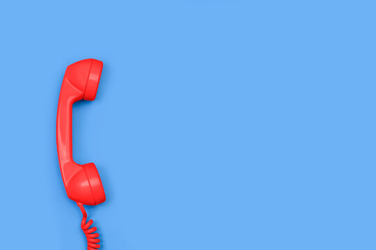 Tubo de teléfono antiguo con cable de color rojo sobre un fondo azul liso y aislado. Vista superior y de cerca. Copy space
