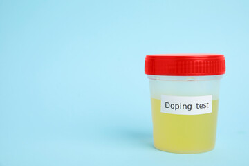Jar with urine sample on light blue background, space for text. Doping control