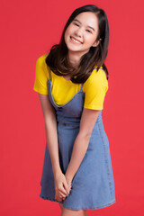 Asian girl Wear yellow shirt and short skirt pose in advertising and presenting goods and contents gesture with friendly smile face on red background.