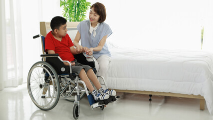 Smiling young Asian doctor massaging hand of little ethnic patient with disability