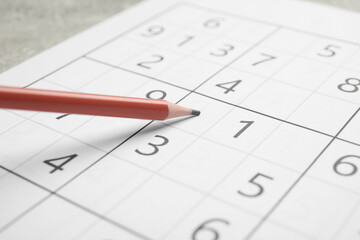 Sudoku and pencil on grey table, closeup