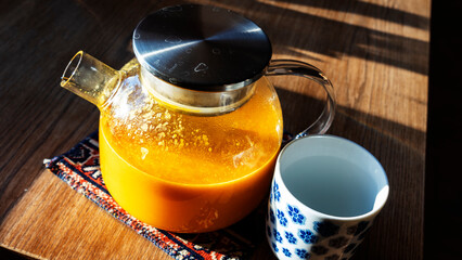 Close-up view of glass kettle with cup on the wooden table. Flagae tea in glass teapot. Healthy concept.