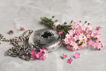 Beautiful Forget-me-not flowers and pocket watch on grey table