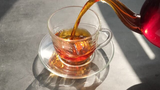 Fresh aromatic herbal tea is poured into a transparent cup. The concept of hot warming vitamin healthy drinks.