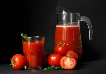 Tomato juice and fresh tomatoes on dark background.