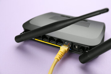 Modern Wi-Fi router on lilac background, closeup