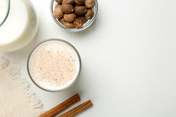 Milk with nutmegs and cinnamon on white table, flat lay. Space for text