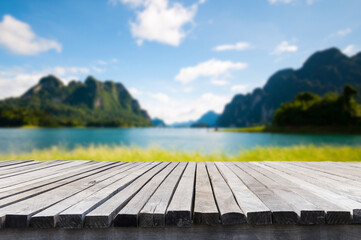 Empty old wooden table in front of blurred background of the lake, mountain, blue sky among bright sunlight on a clear day. Can be used for display or montage for show your products.
