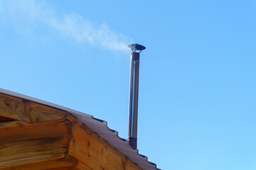 Smoke from the chimney of the forest house. Heating winter wooden hut in the cold. selective focus