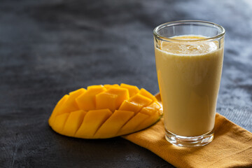 Indian traditional lassi drink with mango on dark background