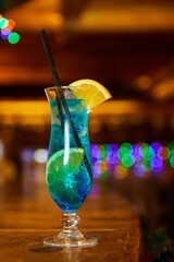 Blue non-alcoholic cocktail with lemon decorated with an orange slice on the bar. Close-up, selective focus
