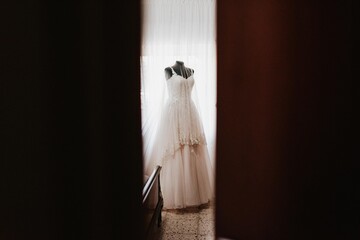Vestido de novia blanco en habitación. Vestido en maniquí. Preparativos el día de la boda en casa de la novia.
