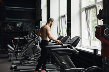 Obraz na płótnie Canvas Man running in a gym on a treadmill concept for exercising, fitness and healthy lifestyle