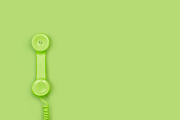 Tubo de teléfono antiguo con cable de color verde sobre un fondo verde liso y aislado. Vista...