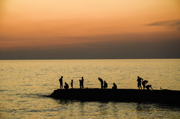 Sunset on the Black Sea. Silhouettes of fishermen on the pier.