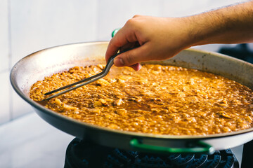 Cooking paella chef checks readiness with tweezers - Spanish food