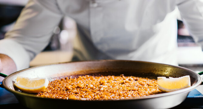 chef holding paella on the table close-up - Spanish food