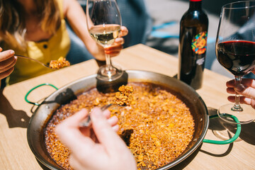 Time to eat paella. Several hands with cutlery begin to eat paella at a table in a seafood and...