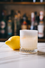 White Russian at the bar on a blurred background of alcohol. Party at a nightclub for adults. Milkshake with cream, vodka and lemon