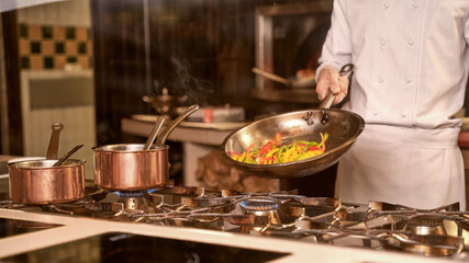 Restaurant chef cooking pepper slices on a pan