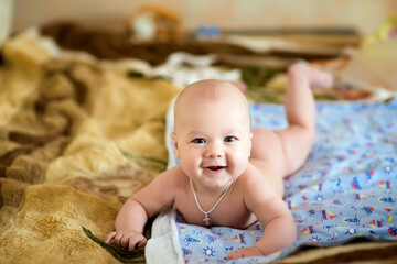 A newborn baby is resting in bed. Children's room. The naked baby is lying on his stomach. Family morning at home. image with selective focus