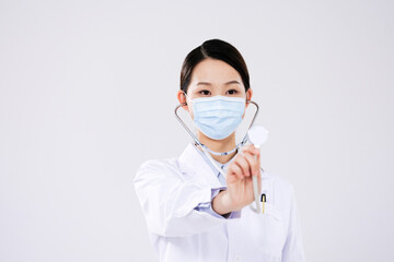 A woman doctor wearing a mask uses a stethoscope