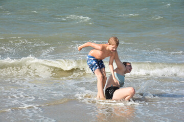 Two children play in  the sea on a sandy beach