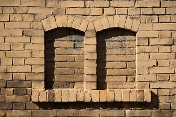Alte Ziegelstein Fassade mit zwei zugemauerten Rundbogen Fenstern. Ein Symbol für Abgeschiedenheit, Sicherheit und Beendigung