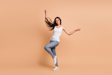 Fototapeta na wymiar Full length photo portrait of girl dancing standing on one leg isolated on pastel beige colored background