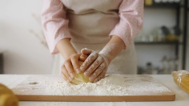 Slow-mo of woman hands kneading dough on kitchen table, baking homemade bread