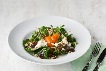 Healthy salad with persimmons on a rustic background. Vegetarian menu, healthy food. Prevention of vitamin deficiency.