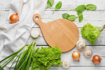 Cutting board with vegetables and herbs on light wooden background