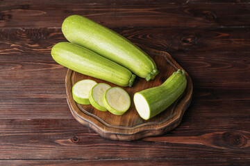 Cutting board with squash on wooden background