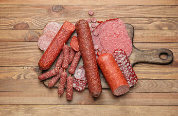 Board with tasty sausages on wooden background