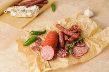 Parchment with tasty sausages on color background