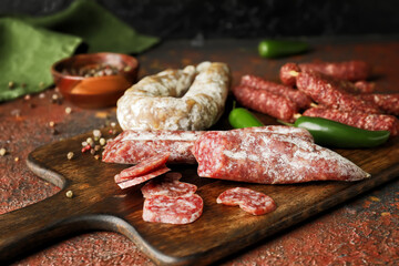 Cutting board with tasty sausages on grunge background