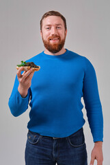 young man with a sandwich with wild black beluga caviar on a light uniform background