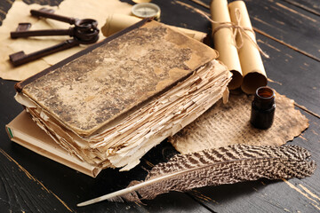 Old book, feather, compass, scrolls and keys on dark wooden background