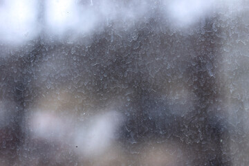 Streaks and traces of raindrops on the dirty window glass. Blurry and unfocused background.