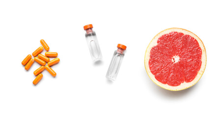 Bottles with vitamin C, pills and grapefruit on white background