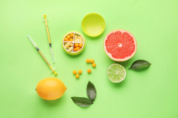 Syringes with vitamin C, pills and citrus fruits on color background