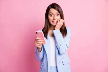 Photo of young beautiful woman bite fingers nervous panic fail dislike use smartphone isolated over...