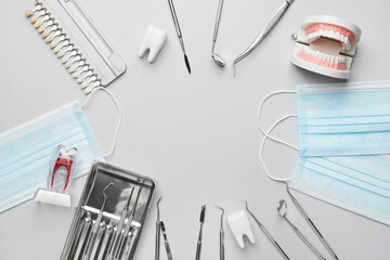 Frame made of dentist's tools, jaw model and teeth color samples on light background