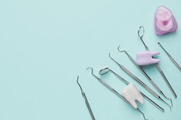 Dentist's tools and plastic teeth on color background